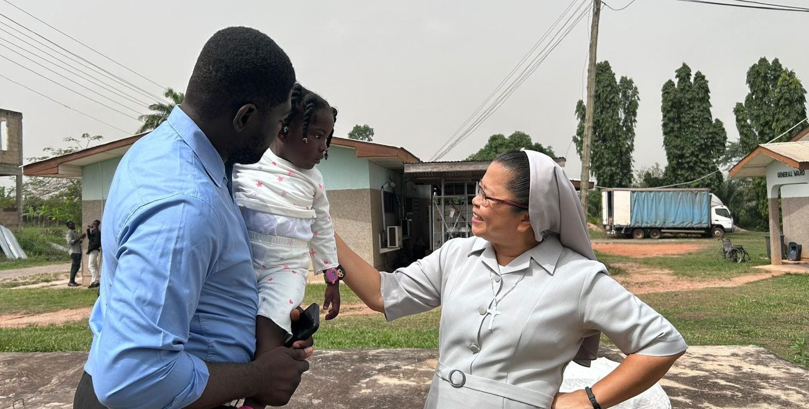 Una hermana hospitalaria conversa con un padre y su hija durante una visita comunitaria en el marco de la Semana Misionera.